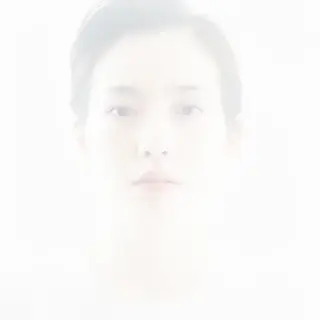 A high-key portrait of a person against a bright white backg