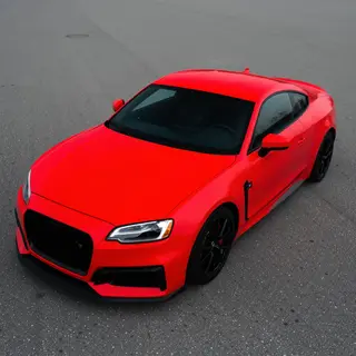 A bright red sports car parked on a gray asphalt road — the 