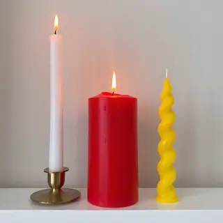 A tall thin white candle, a short fat red candle, and a medi