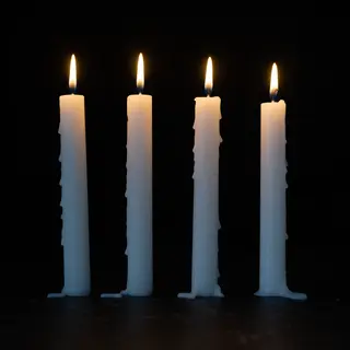 Exactly 4 white candles standing on a dark surface