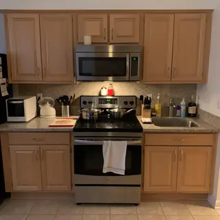 A kitchen with pots, pans, a stove, and a cutting board but 