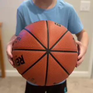 A child holding a basketball, both at correct relative sizes