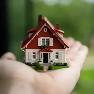 A miniature house sitting on the palm of someone's hand