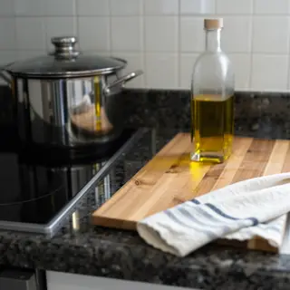 A kitchen counter with a stainless steel pot, a wooden cutti