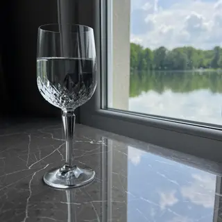 A crystal wine glass on a polished marble counter next to a 