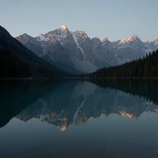 A mountain range reflected in a still alpine lake, with the 