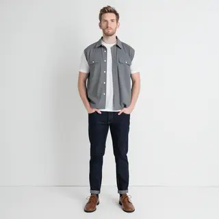 A man standing straight facing the camera, hands in pockets,