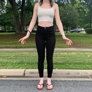 A person standing in a neutral pose in a park, full body vis