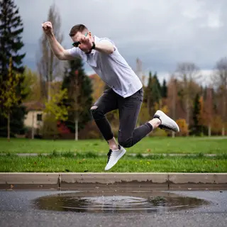 A man captured mid-jump over a puddle, body in the air with 