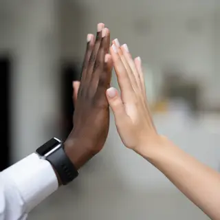 Two people doing a high-five, palms meeting with all fingers