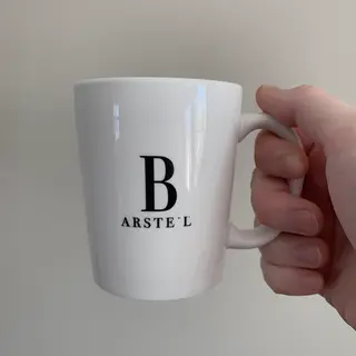 A person holding a white ceramic coffee mug by the handle wi