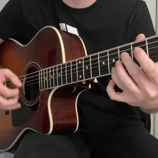 A person playing an acoustic guitar with left hand on the fr