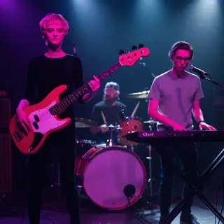 Three musicians on stage: a tall woman with short pink hair 