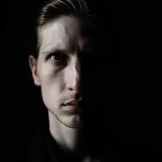 A portrait with dramatic split lighting — half the face brig