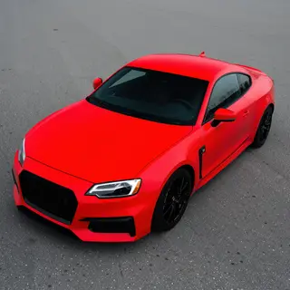A bright red sports car parked on a gray asphalt road — the 