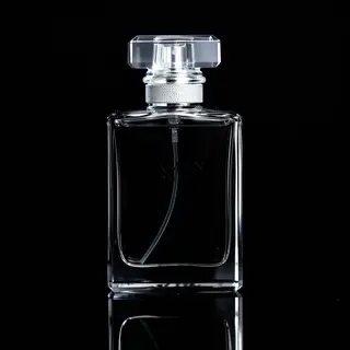 A clear glass perfume bottle on a reflective black surface w