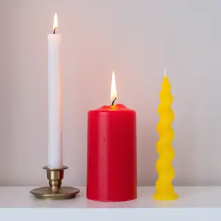 A tall thin white candle, a short fat red candle, and a medi