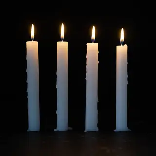 Exactly 4 white candles standing on a dark surface