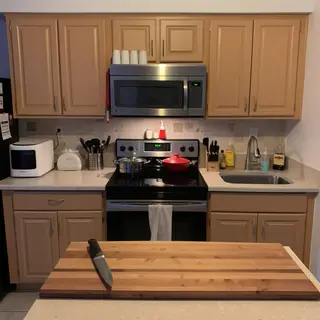 A kitchen with pots, pans, a stove, and a cutting board but 