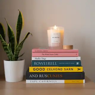 A candle on top of a stack of books, the books next to a pot
