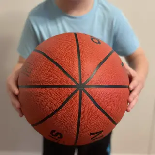 A child holding a basketball, both at correct relative sizes