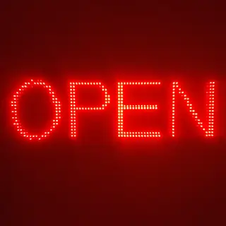 The word 'OPEN' displayed on a red LED sign with glowing pix