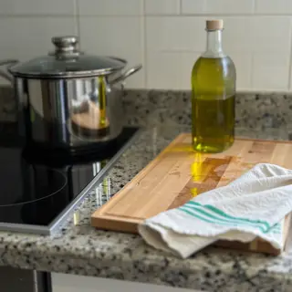 A kitchen counter with a stainless steel pot, a wooden cutti
