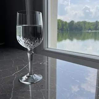 A crystal wine glass on a polished marble counter next to a 