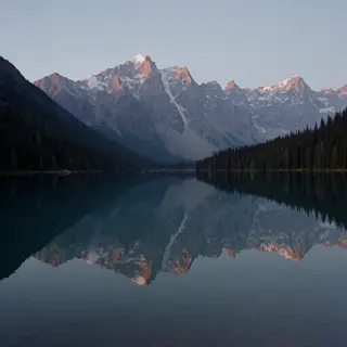 A mountain range reflected in a still alpine lake, with the 