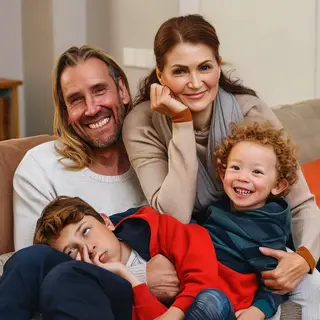 A family photo with four people: a father beaming with pride