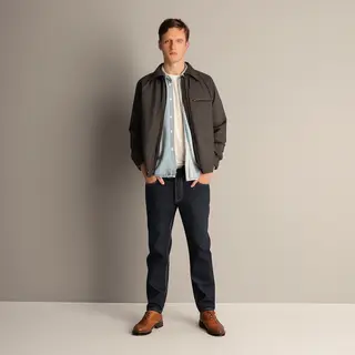A man standing straight facing the camera, hands in pockets,