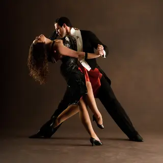 Two tango dancers in a close embrace, the man dipping the wo