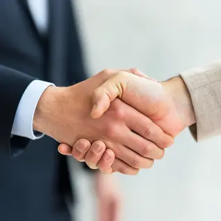 Two people shaking hands in a professional setting, all fing