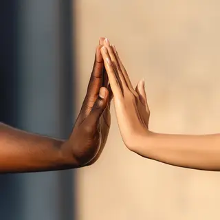 Two people doing a high-five, palms meeting with all fingers