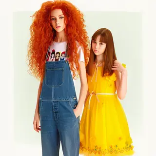 Two friends posing: one tall with curly red hair in denim ov