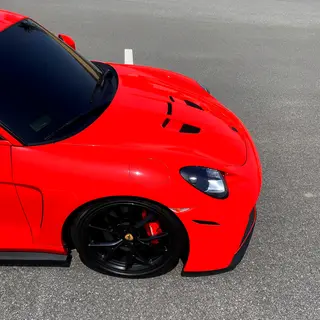 A bright red sports car parked on a gray asphalt road — the 