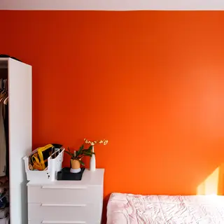 A bedroom wall painted in #FF6B35 (burnt orange) with white 
