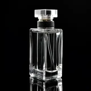 A clear glass perfume bottle on a reflective black surface w