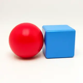 A red ball and a blue cube sitting side by side on a white s