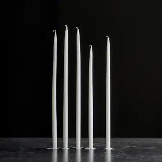 Exactly 4 white candles standing on a dark surface