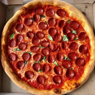 A pepperoni pizza with tomato sauce, basil, and crust but ab