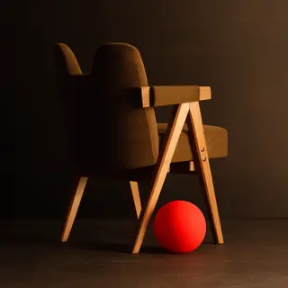 A red ball underneath a wooden chair