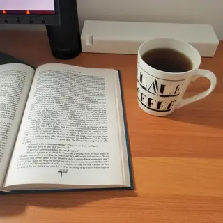 A coffee mug next to an open book on a desk