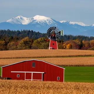 A landscape with a red barn in the foreground at large scale