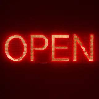 The word 'OPEN' displayed on a red LED sign with glowing pix