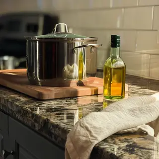 A kitchen counter with a stainless steel pot, a wooden cutti