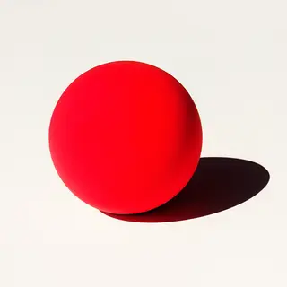 A red sphere on a white surface with a single shadow cast to