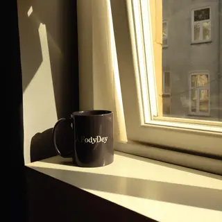 A coffee mug on a sunny windowsill casting a sharp shadow to
