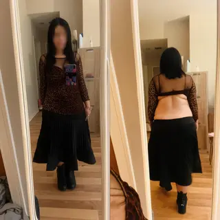 A woman standing in front of a full-length mirror, her refle