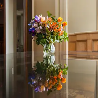 A vase of flowers on a glass table with a clear reflection v